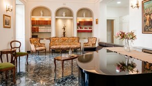 A spacious living room with a marble floor, a grand piano, and a bookshelf with books and decorative items. - The One - Luxury Apartment with Piano (Bari)