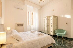 A hotel room with a bed, a vanity with a mirror, a green chair, and a sign on the bed. - The One - Luxury Apartment with Piano (Bari)