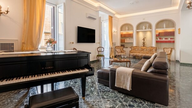 A living room with a grand piano, a sofa, a coffee table, and a bookshelf. - The One - Luxury Apartment with Piano (Bari)