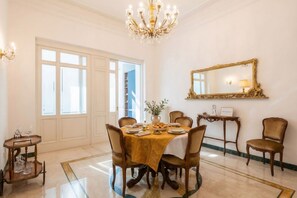 A dining room with a chandelier, a large mirror, and a table set for four. - The One - Luxury Apartment with Piano (Bari)