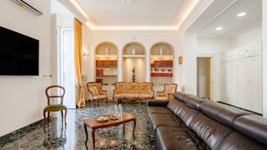 A living room with a sofa, chairs, a TV, and a bookshelf. - The One - Luxury Apartment with Piano (Bari)