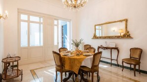 A dining room with a chandelier, a large mirror, and a table set for four. - The One - Luxury Apartment with Piano (Bari)