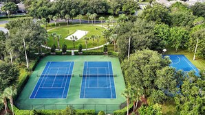 Ein Tennisplatz, umgeben von üppigem Grün und einem kleinen Teich.