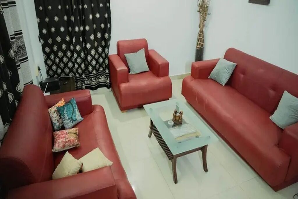 Una sala de estar con sofás rojos, una mesa de centro de vidrio y cortinas estampadas.
