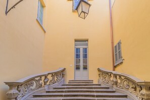 Una escalera con barandillas decorativas que lleva a una puerta con un ventanal.