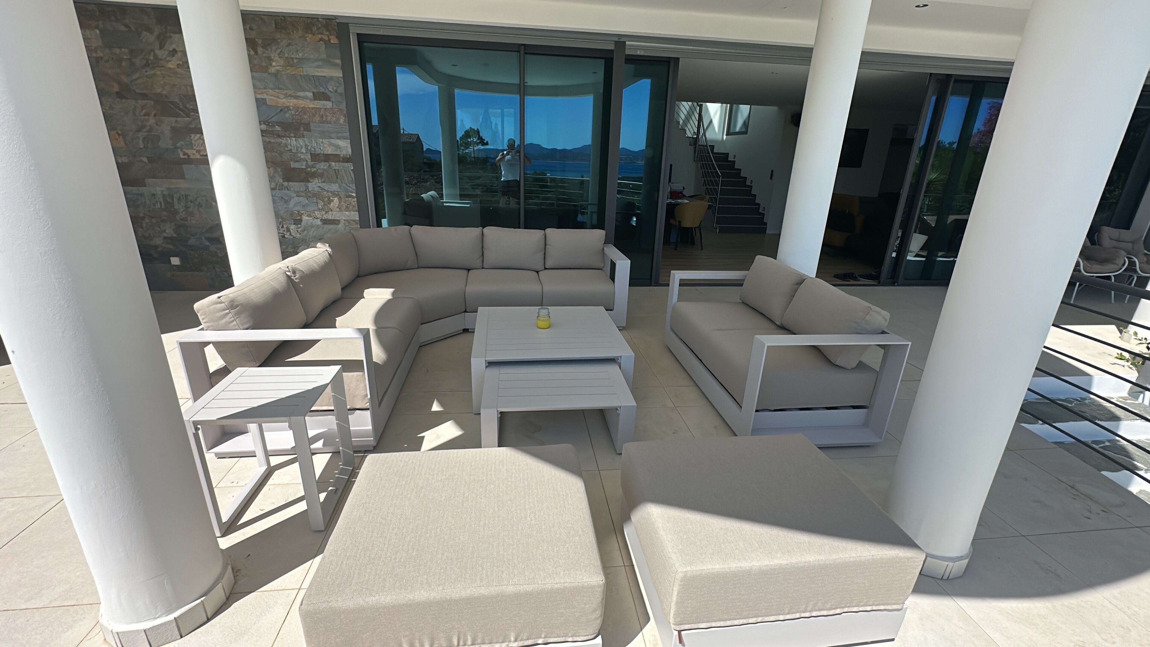 A modern outdoor living area with a sectional sofa, two side tables, and a coffee table.