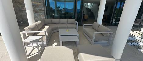 A modern outdoor living area with a sectional sofa, two side tables, and a coffee table.
