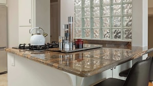 A kitchen with a central island, a hanging pot rack, a gas stove, and a window with a decorative grid.
