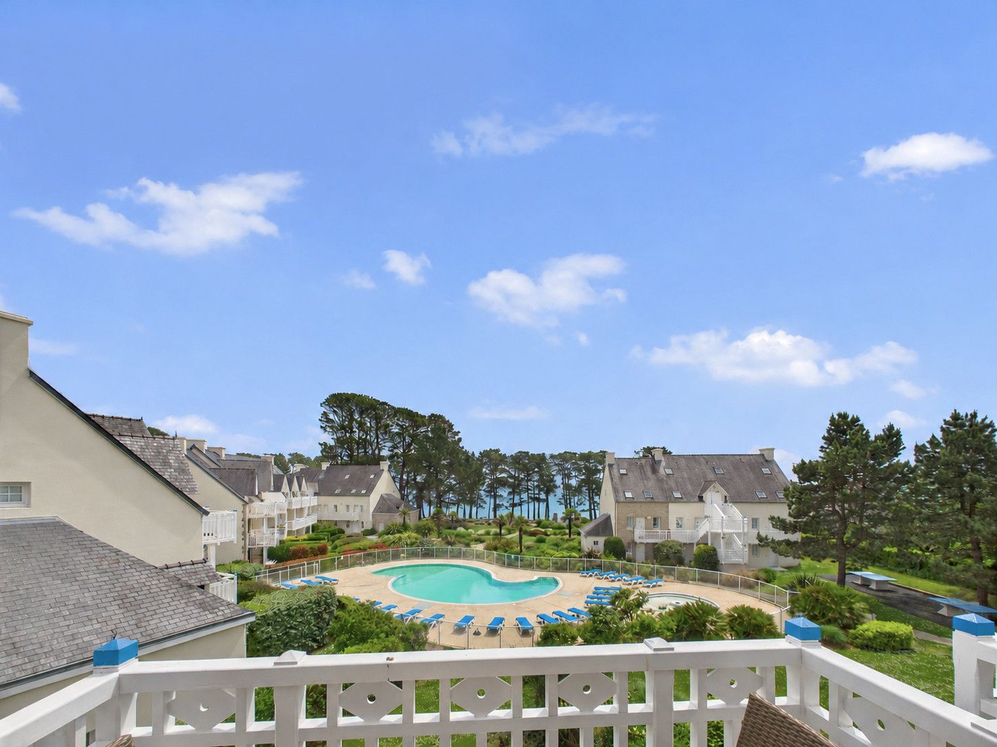 A pool area with lounge chairs and a clear sky.