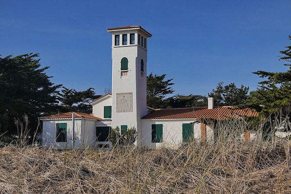 A white church with a bell tower, green shutters, and a tiled roof.