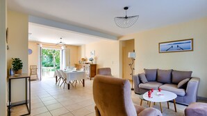 A spacious living area with a sofa, armchairs, a dining table, and a ceiling fan. - Spacious house for 4 with garden and terrace (Pleurtuit)