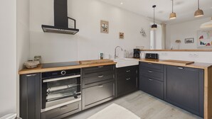 Une cuisine moderne avec des meubles de couleur sombre, des appareils en acier inoxydable et un plan de travail en bois.