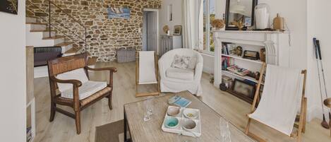 A cozy living room with a stone wall, a fireplace, a bookshelf, and a dining area with a table set for two.