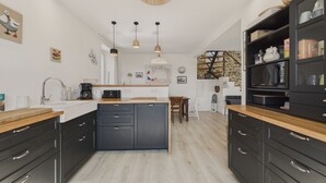 Une cuisine moderne avec des meubles de couleur sombre, un plan de travail en bois et des luminaires suspendus.