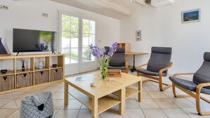 A modern living room with a TV, seating, a table, and a view of the outdoors. - 500 m from the beach - House for 6 - Terrace (L'Epine)