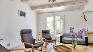 A modern living room with two grey armchairs, a wooden coffee table, and a vase with purple flowers. - 500 m from the beach - House for 6 - Terrace (L'Epine)