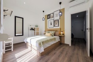 A bedroom with a bed, bedside tables, a wardrobe, and a mirror. - Apartment 2 in Ronda Sant Pau (Barcelona)