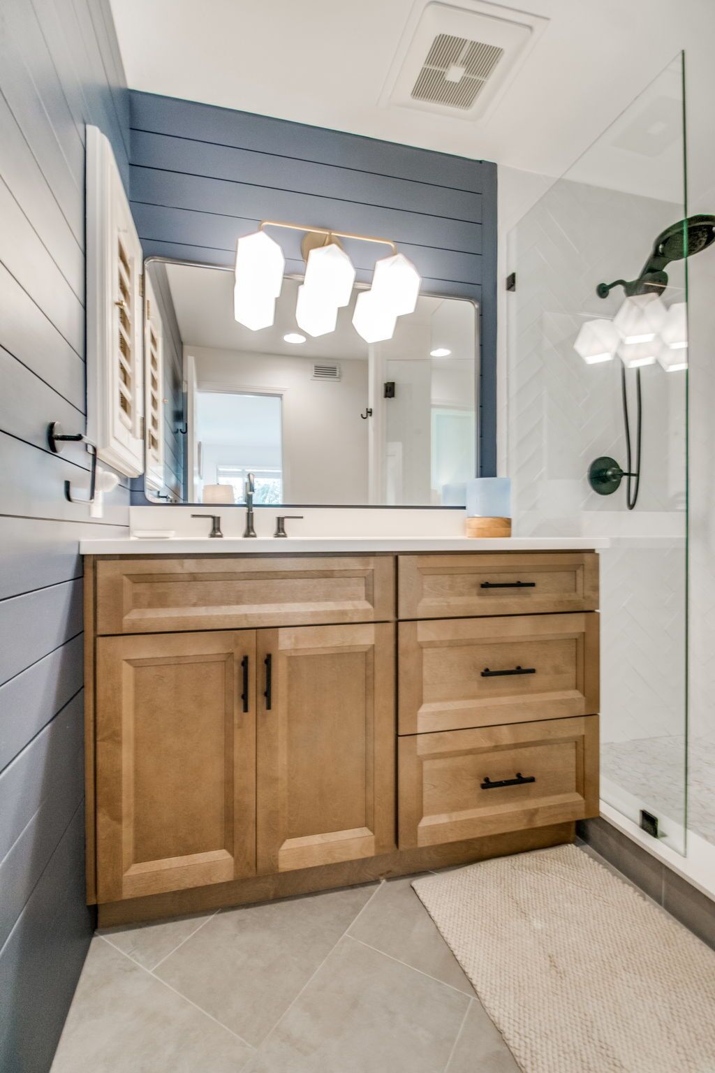 A bathroom with a wooden vanity, a large mirror, and a shower area.