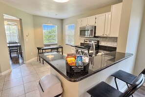 A kitchen with a welcome sign, a microwave, and a refrigerator. - Cozy 4BR Family Home Near Disney at Montego Bay (Kissimmee)