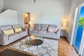 A living room with two grey sofas, a glass coffee table, and a patterned rug. - Cozy 4BR Family Home Near Disney at Montego Bay (Kissimmee)