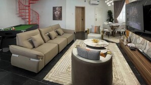 Ein modernes Wohnzimmer mit Billardtisch, einer Couch, einem Couchtisch und einem Fernseher.
