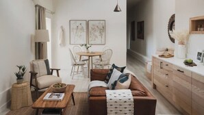 A cozy living room with a brown sofa, wooden coffee table, and a dining area with a round table and chairs. - Longstones Avebury – Ridgeway (Marlborough)