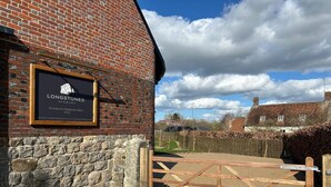 A brick building with a stone foundation, a wooden gate, and a signboard. - Longstones Avebury – Ridgeway (Marlborough)