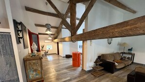 A spacious living room with exposed wooden beams, a large sofa, and a coffee table. - Quality LOFT for 4 people (Lamalou-les-Bains)
