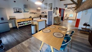 A spacious kitchen with wooden flooring, a central island, and a dining area with a large table and chairs. - Quality LOFT for 4 people (Lamalou-les-Bains)
