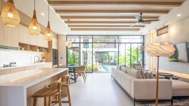 A modern kitchen with a central island, wooden bar stools, and pendant lighting. - Chic 3BR Hideaway Canggu • AC • 5min to Beach (Kecamatan Kuta Selatan)