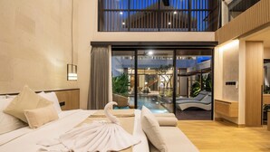 A modern hotel room with a large bed, a sofa, and a view of a pool and outdoor area. - Chic 3BR Hideaway Canggu • AC • 5min to Beach (Kecamatan Kuta Selatan)