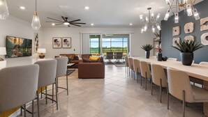 A modern living room with a sofa, chairs, a dining table, and a ceiling fan.