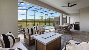 A covered patio area with outdoor furniture, a pool, and a grill.