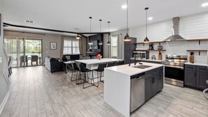 A modern kitchen with a central island, built-in appliances, and pendant lighting.