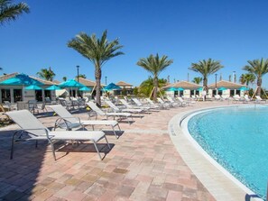 A poolside area with lounge chairs and umbrellas, palm trees, and a clear blue sky. - PROMO Magical 8BR Villa, Game Room, Resort - by Blue Sky Villas (Davenport)