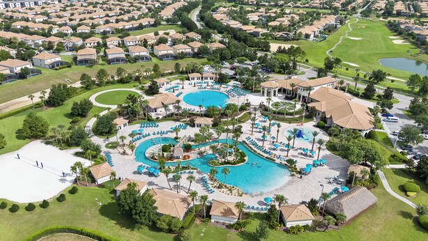 An aerial view of a resort with multiple swimming pools, sun loungers, and a golf course.