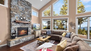 A spacious living room with a stone fireplace, large windows, and a cozy sectional sofa.