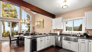 A modern kitchen with white cabinetry, a large island, and a view of the outdoors.