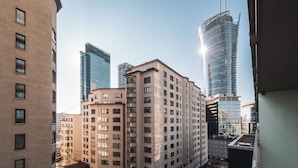 A multi-story building with a flat facade and rectangular windows, surrounded by taller skyscrapers. - Apartamenty Sun&Snow Platinum Towers (Warsaw)