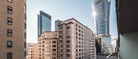 Un edificio a più piani con facciata piatta e finestre rettangolari, circondato da grattacieli più alti.