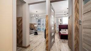 A modern hotel room with a wooden floor, a red upholstered headboard, and a large window. - Apartamenty Sun&Snow Platinum Towers (Warsaw)