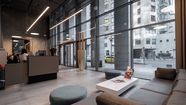 A modern lobby with a reception desk, seating area, and large windows offering views of the street. - Apartamenty Sun&Snow Platinum Towers (Warsaw)