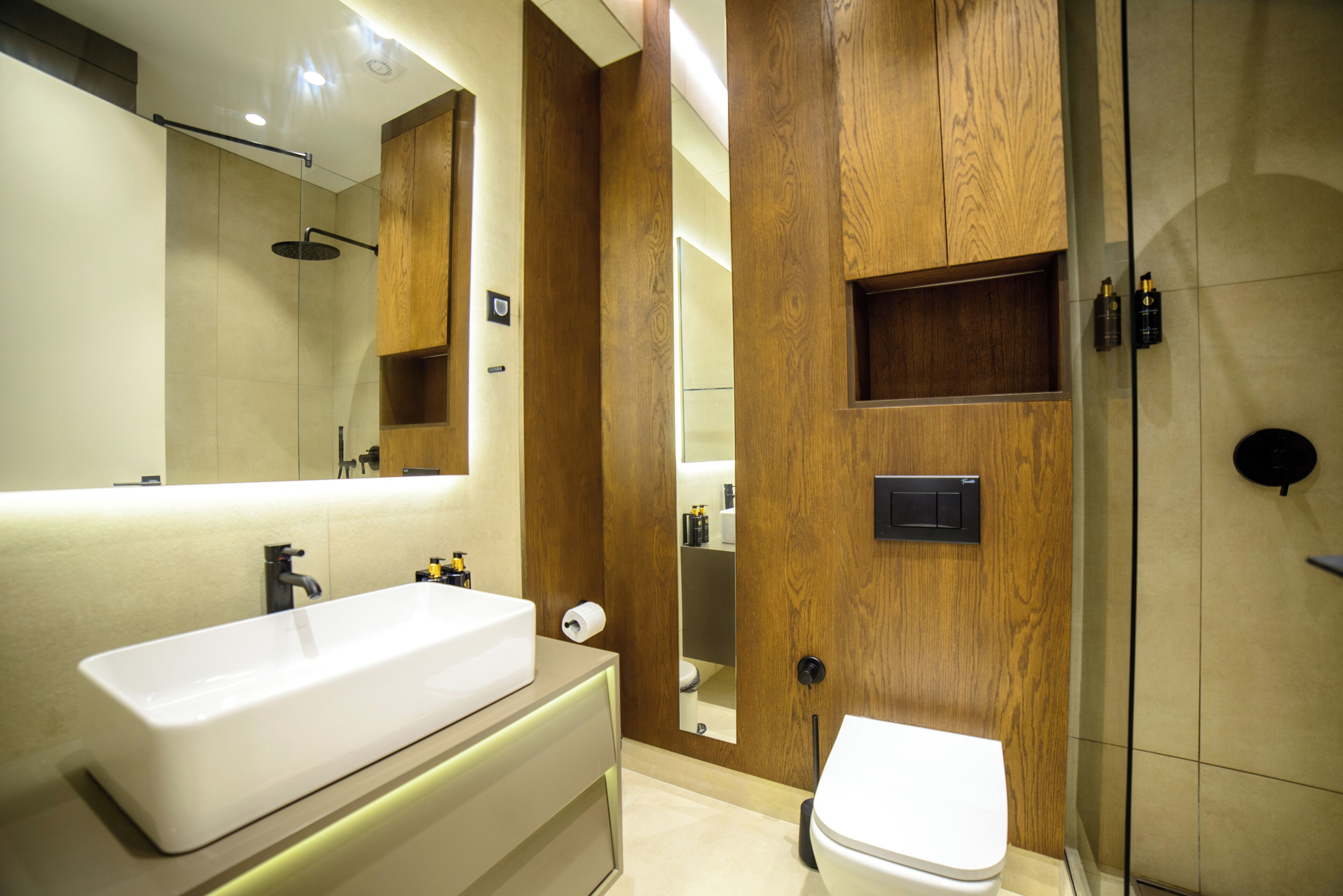 A modern bathroom with a large sink, mirror, and wooden paneling.