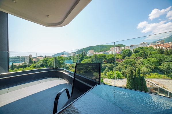 Ein modernes Hotelzimmer mit großem Balkon und Blick auf Stadt und Grünflächen.