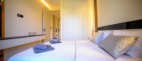 A modern hotel room with a neatly made bed, a bedside table with a lamp, and a large wardrobe.
