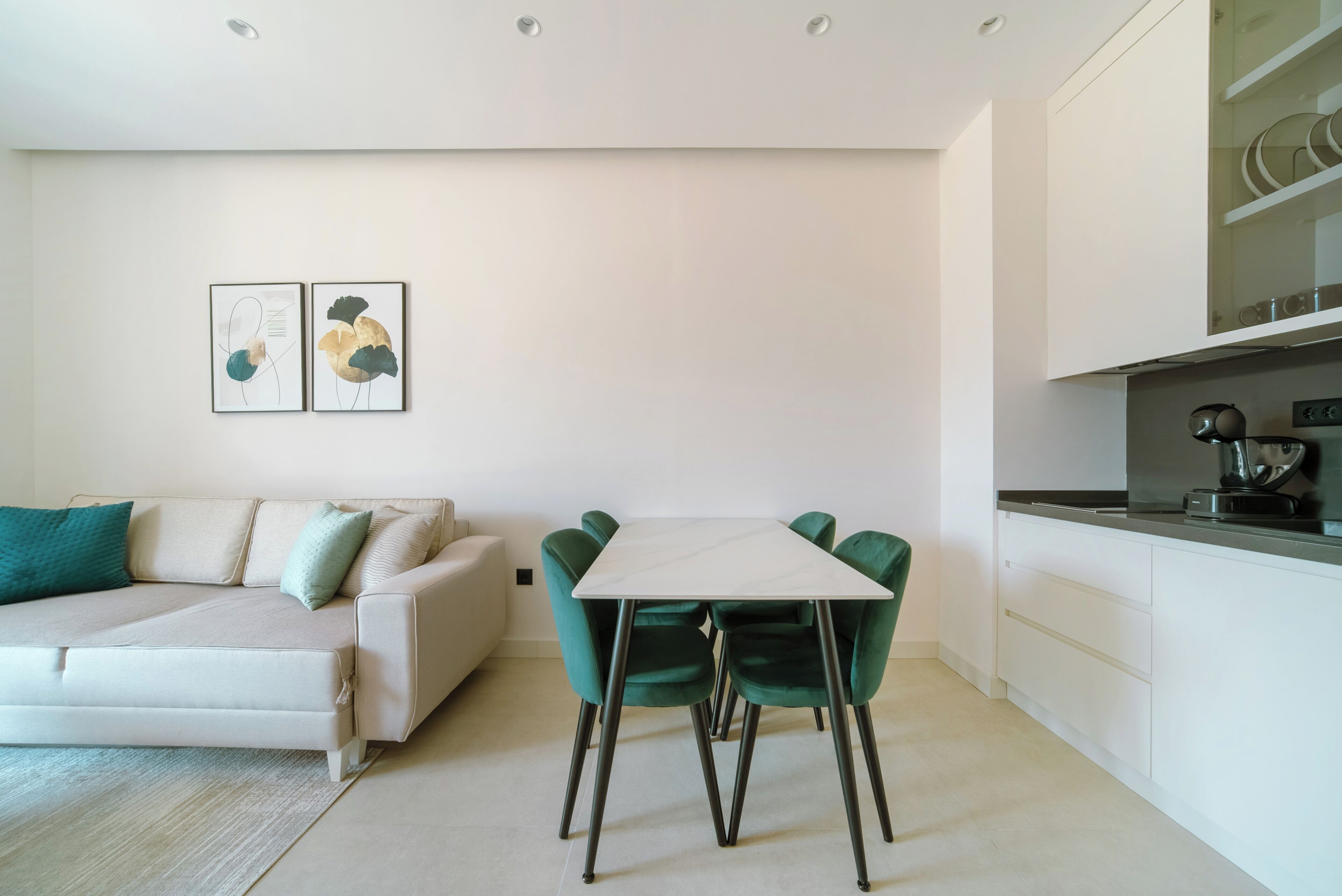 Una sala de estar moderna con un sofá, una mesa de comedor con sillas y una zona de cocina con armarios y encimera.