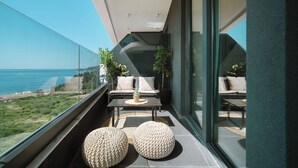 Un balcon moderne doté d’une rambarde en verre, offrant une vue sur un paysage côtier.
