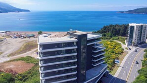 Un immeuble moderne à plusieurs étages, doté d’une façade incurvée, situé près d’une zone côtière et offrant une vue dégagée sur la mer.