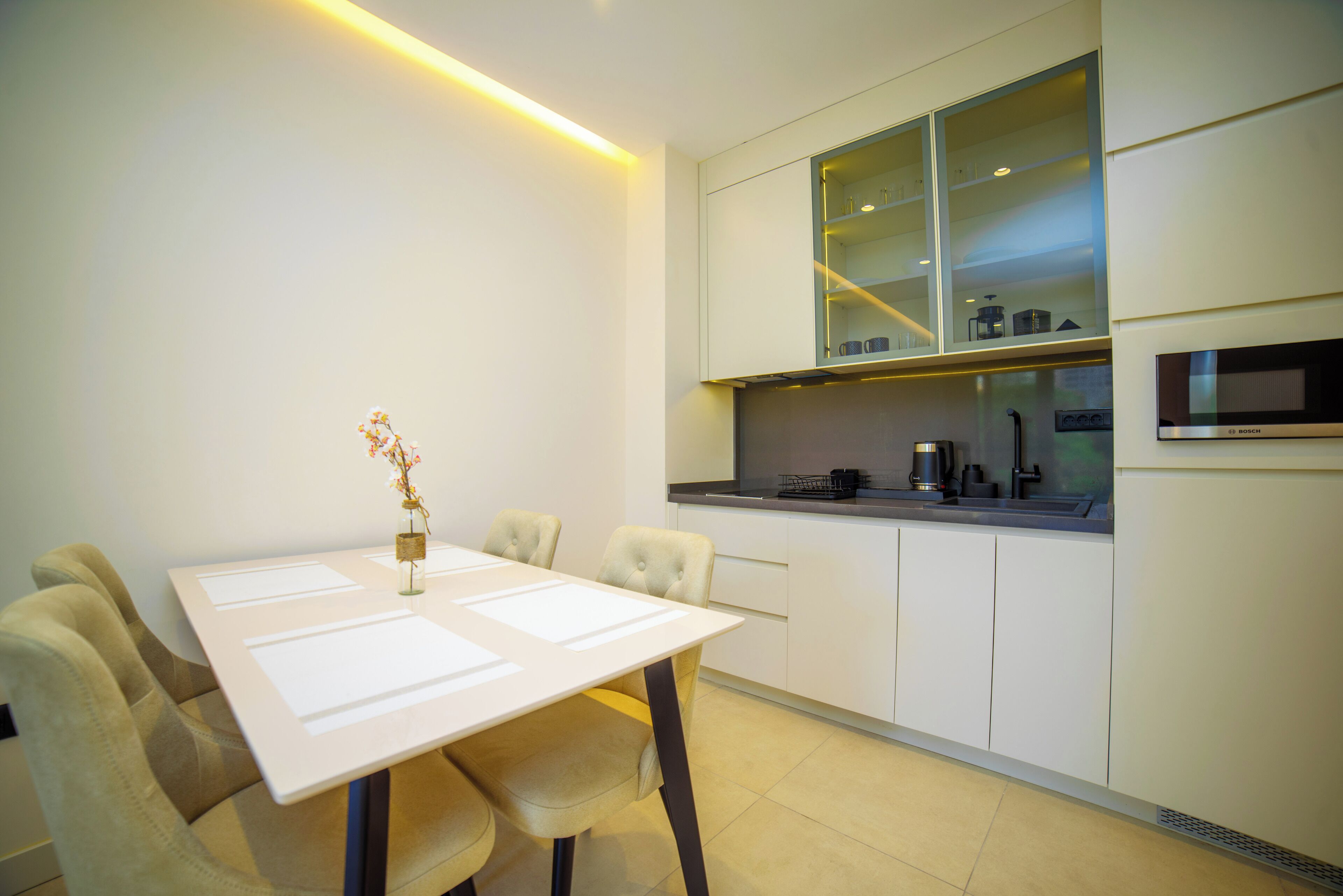 A modern kitchen with white cabinetry, a dining table with chairs, and a built-in microwave.