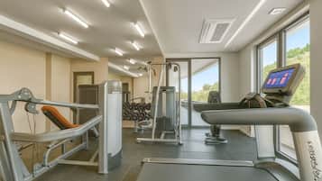 A gym with exercise equipment, a treadmill, and a digital screen.